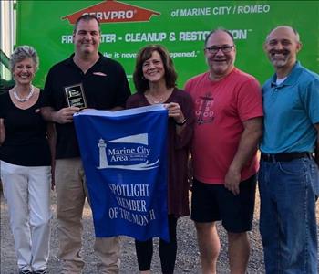 SERVPRO franchise owners standing in front of SERVPRO truck holding up banner award