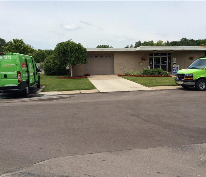 Two SERVPRO trucks parked in front of a building
